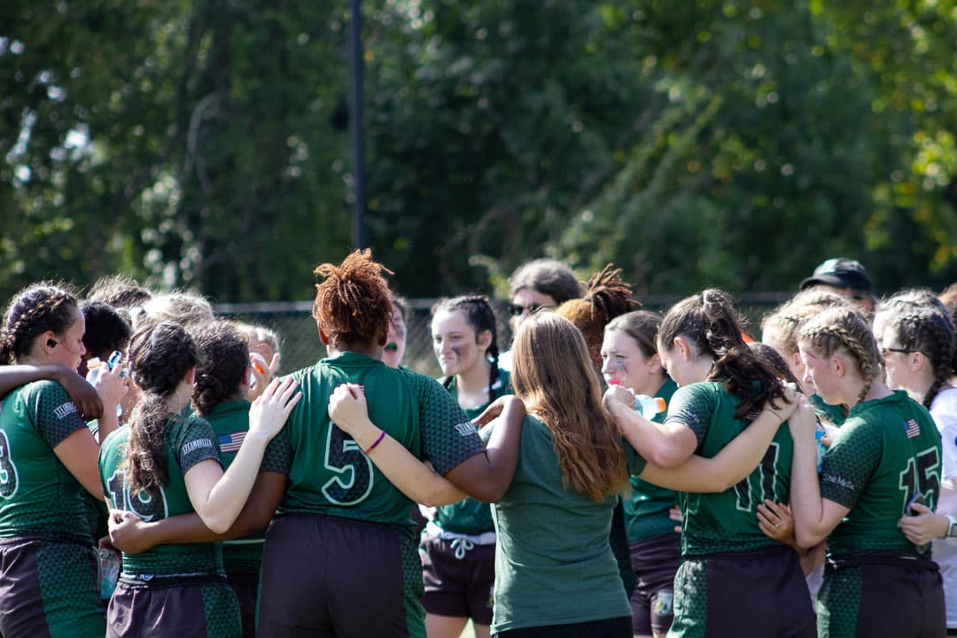 The team huddle, arms around shoulders